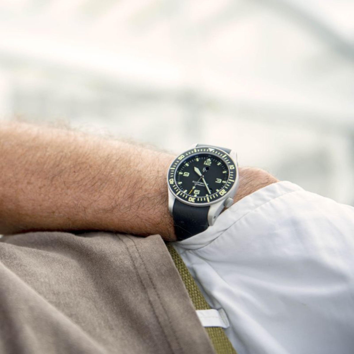 Men's automatic watch worn on wrist, black dial with green accents, black rubber strap.