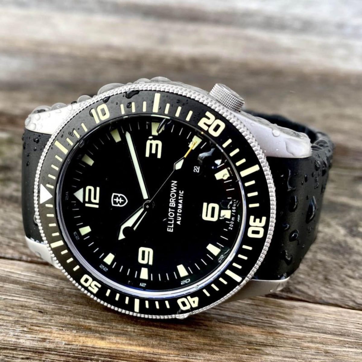 Men's black-dial diver-style automatic watch with silver bezel, black rubber strap, close-up.
