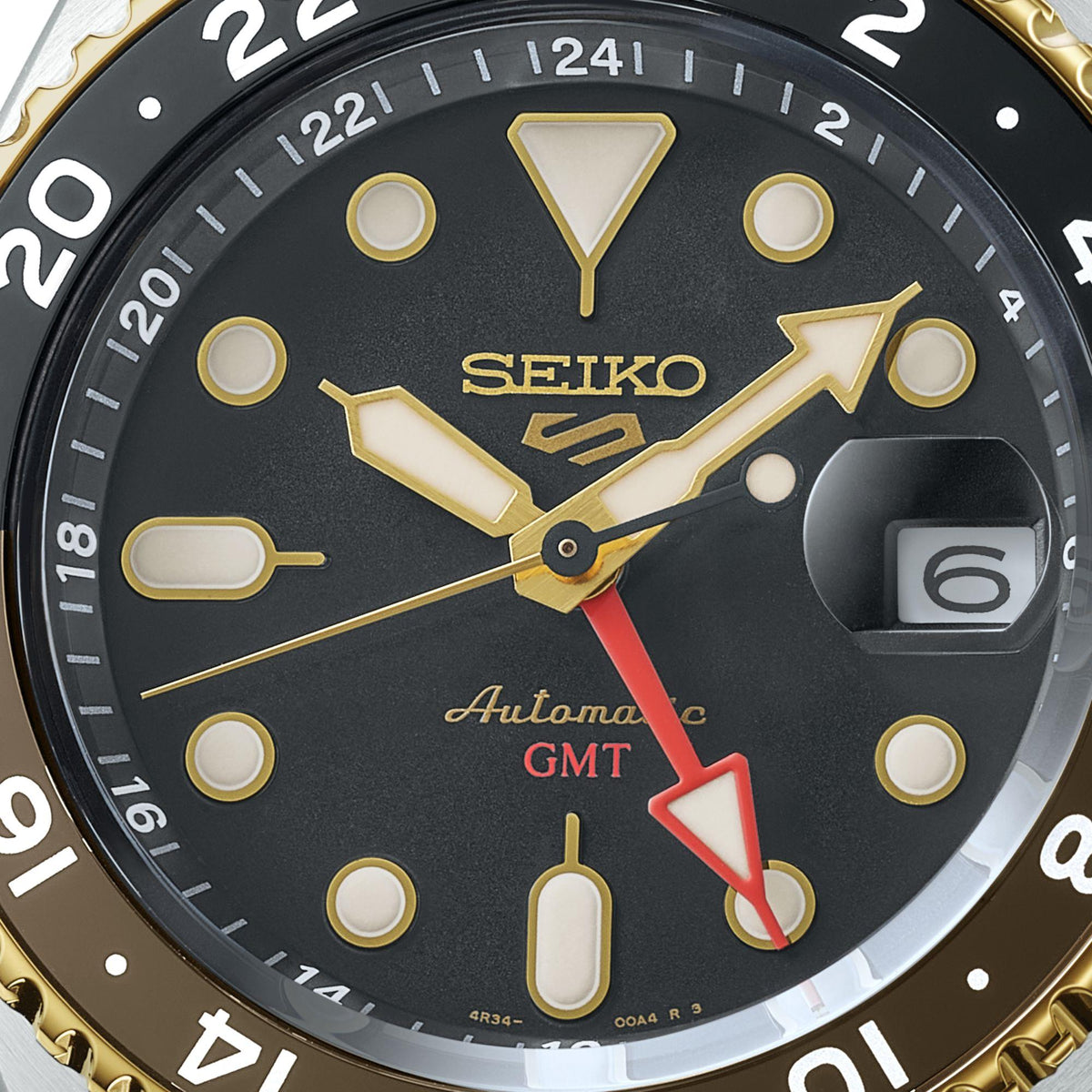 Black GMT dial of an automatic watch with gold markers, date window at 6 o'clock.