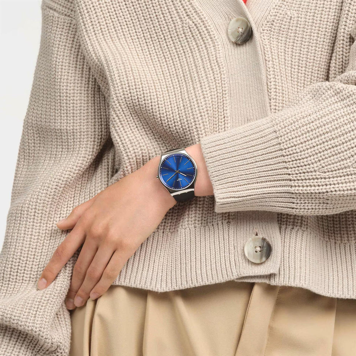 Quartz watch with blue dial on wrist under cream knit sweater sleeve.