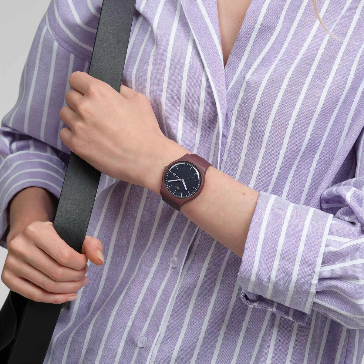 Men’s watch with dark burgundy dial and black silicone strap on wrist