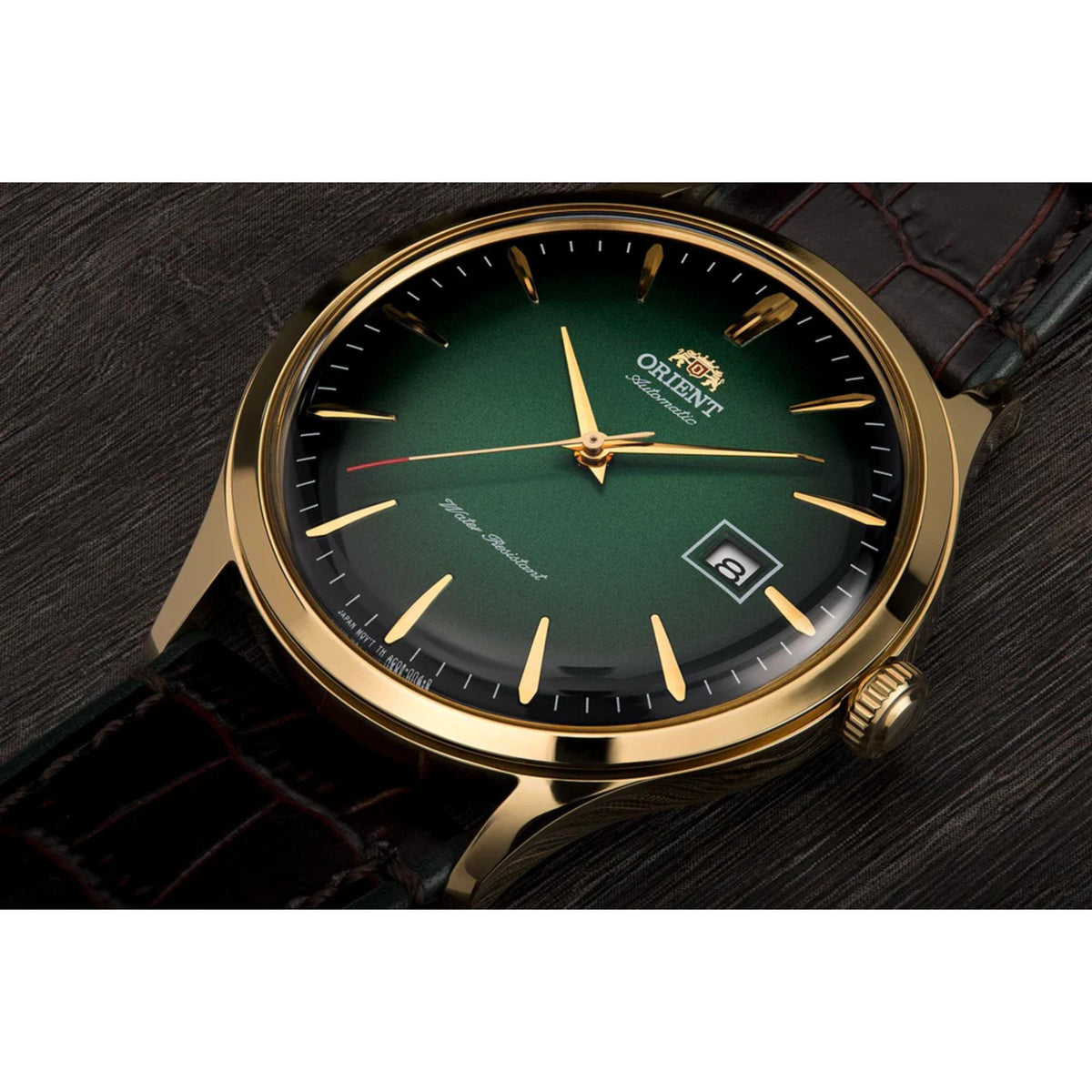 Orient Bambino green dial automatic watch close-up with gold-tone crown and dark leather strap