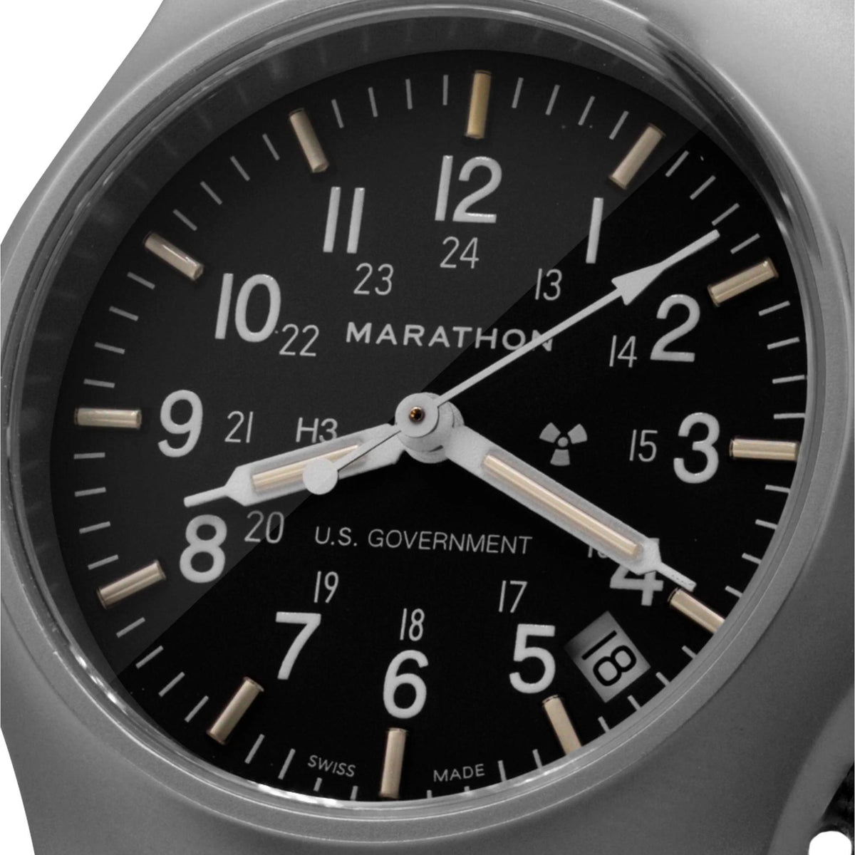 Close-up of black watch dial with luminous hands, Arabic markers, and date window details.