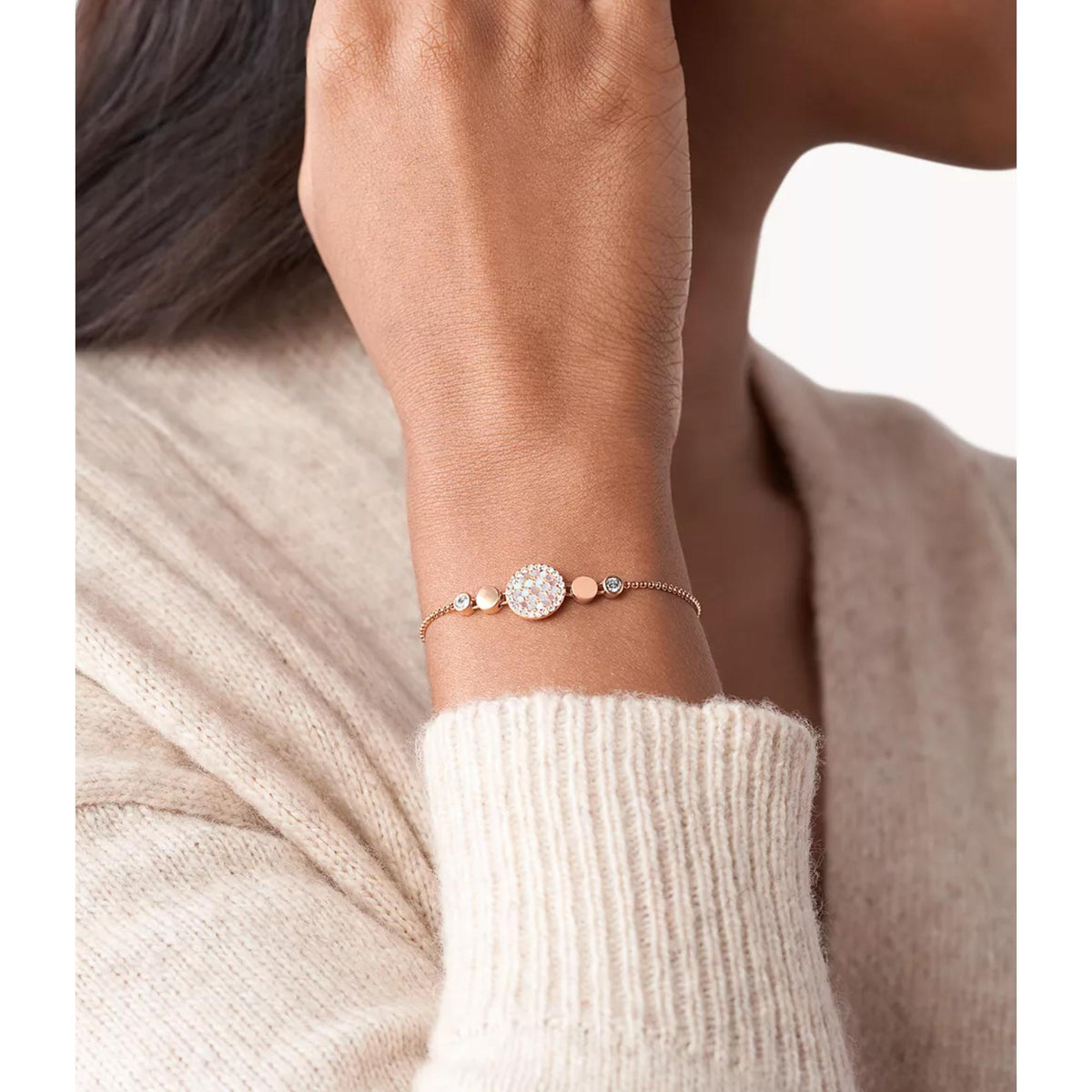 Rose gold-tone bracelet with mother-of-pearl disc charm visible on wrist