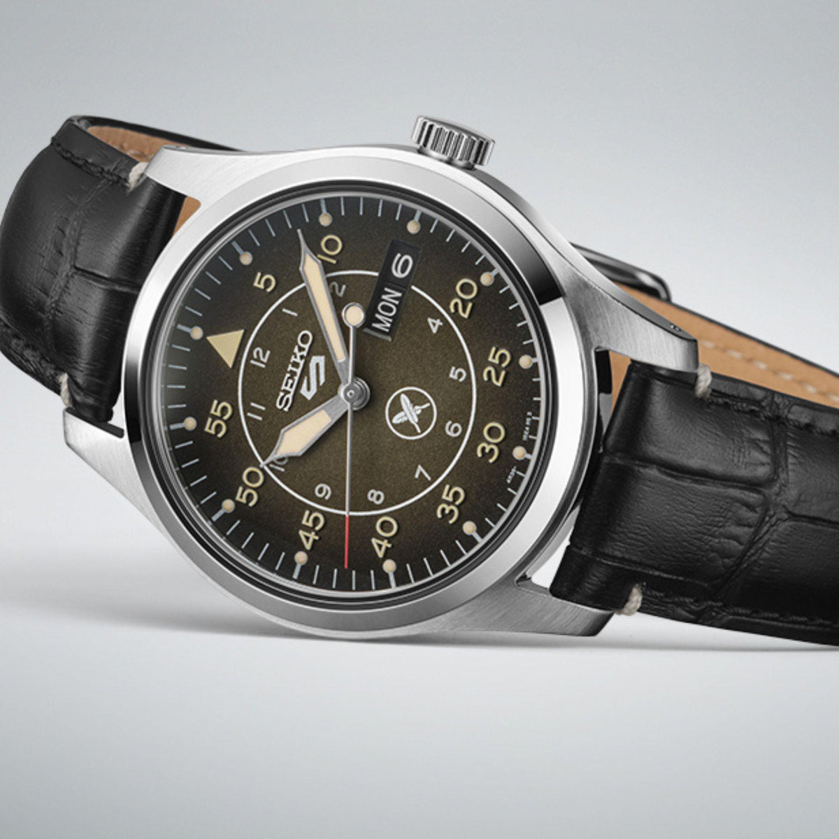 Men's Seiko 5 Sports watch close-up, dark brown dial with gold accents, black leather strap