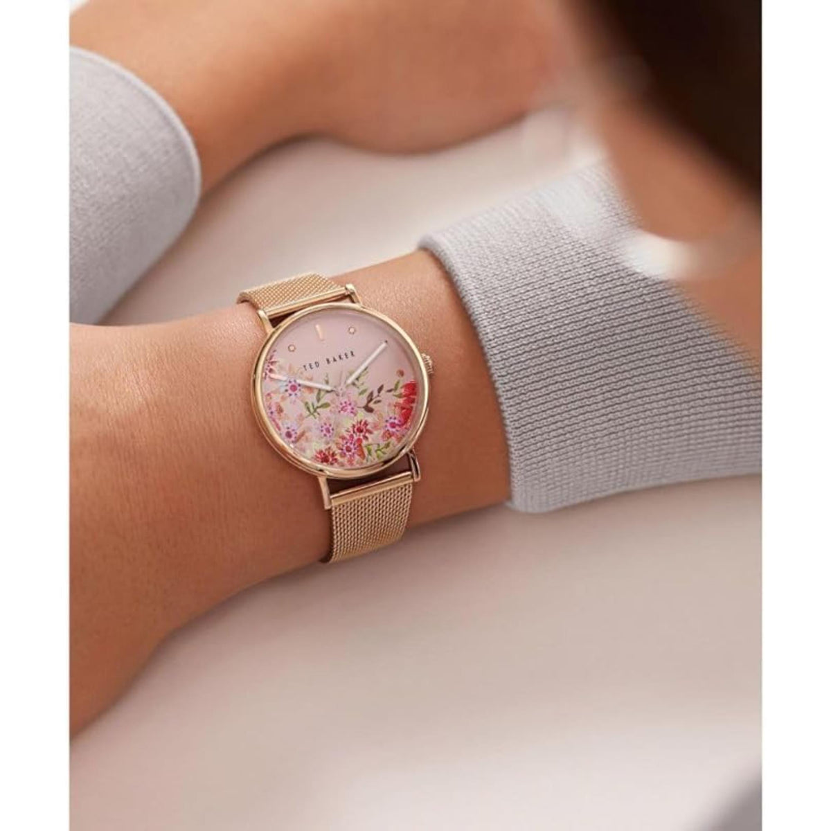 Wrist shot of ladies rose gold mesh band watch with floral pink dial and gold hands