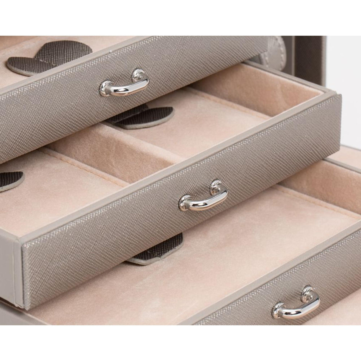 Leather jewelry box interior with textured compartments and silver pull handles on drawers