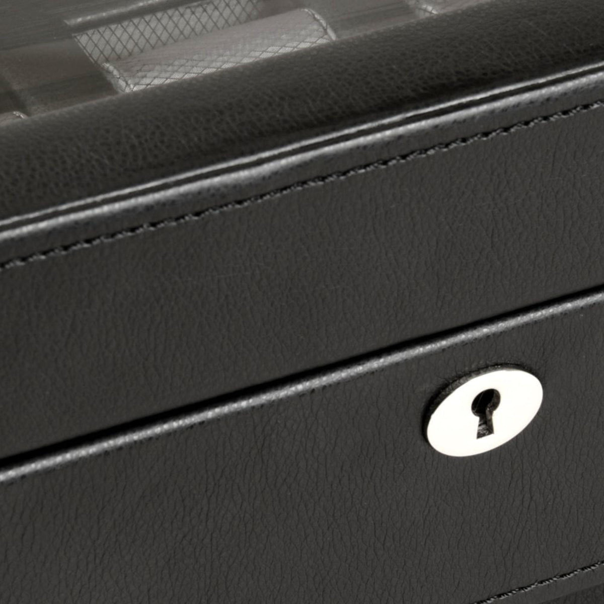 Close-up of black watch box with circular keyhole lock plate and front seam.