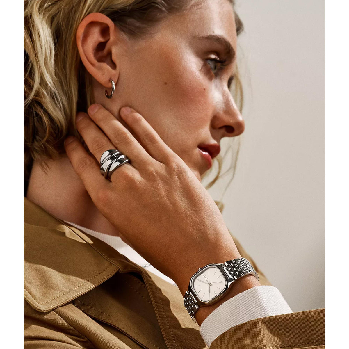 Small silver-tone hoop earrings on model ear, thin rounded hoop