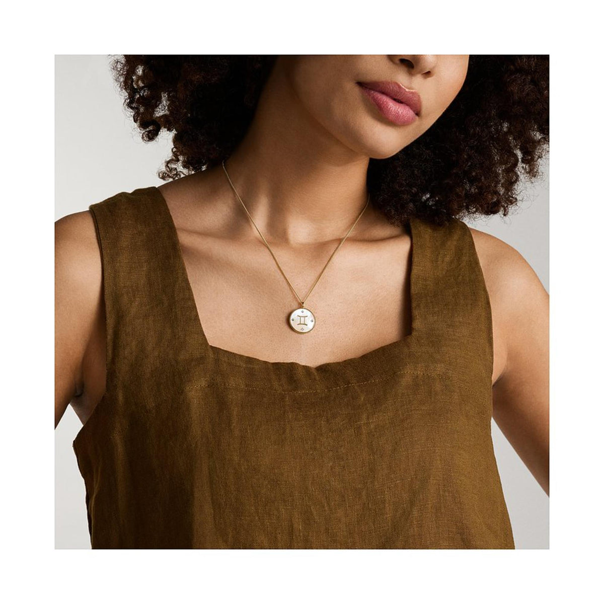 Gold-tone pendant necklace with white mother-of-pearl Gemini charm centered on a chain