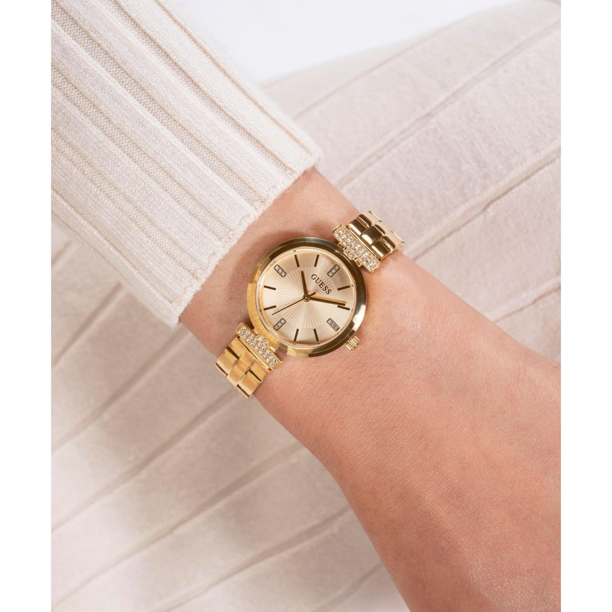 Women's gold-tone round watch with champagne dial and crystal bezel on wrist