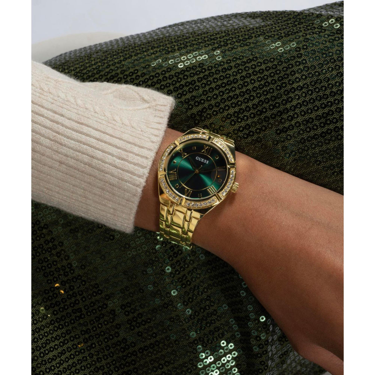 Gold-tone women’s watch on wrist, green dial with crystal bezel and Roman markers