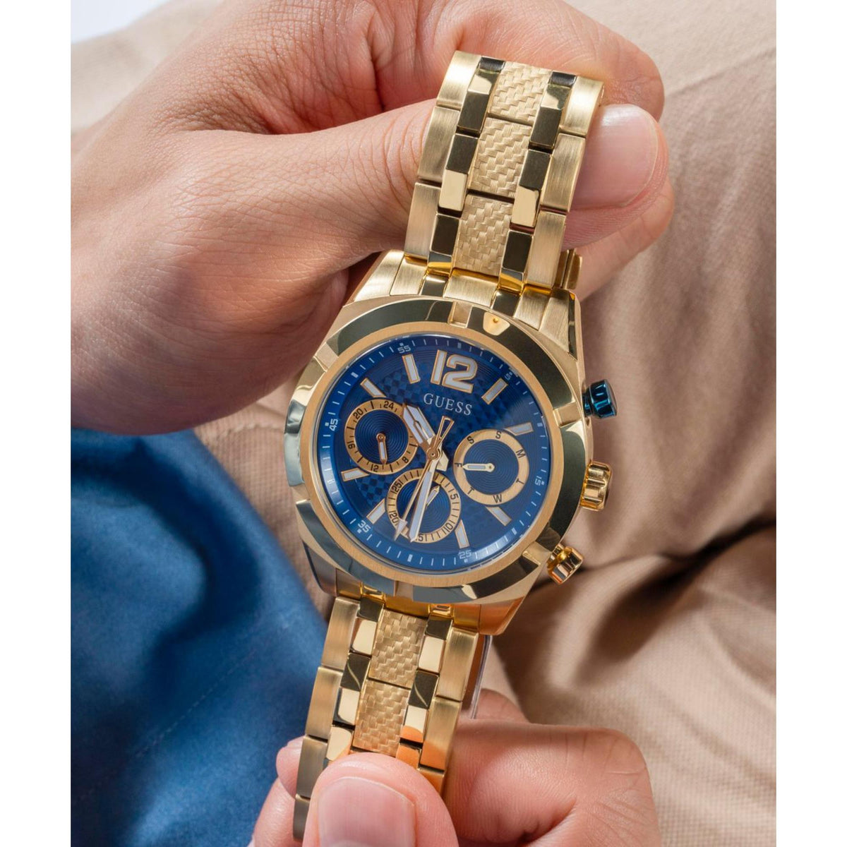 Close-up of gold-tone men's watch with blue dial and subdials on metal bracelet.