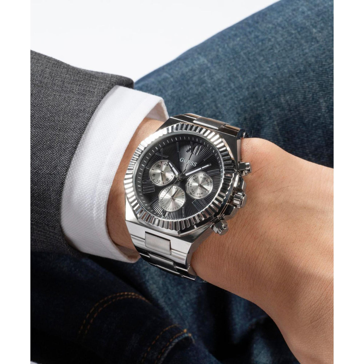 Men's watch close-up on wrist, black dial with subdials and silver metal bracelet.