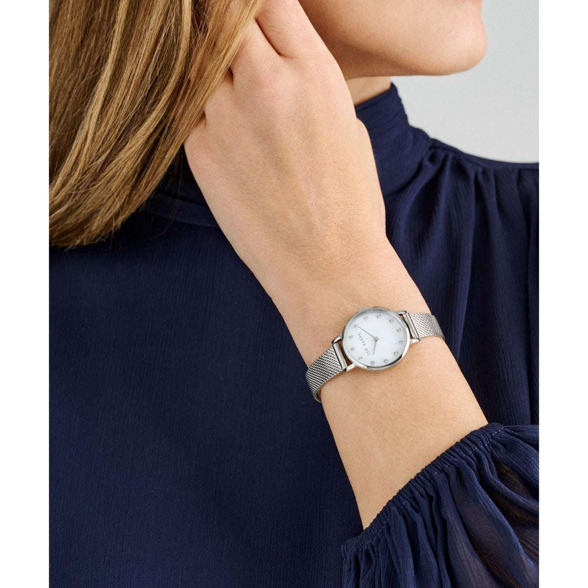 Ladies stainless steel watch on wrist showing white dial and mesh strap
