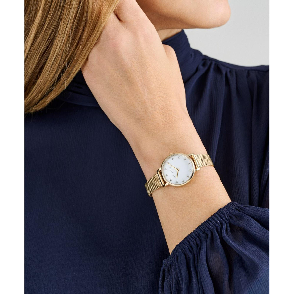 Ladies gold-tone mesh strap watch on wrist, white face with gold hands