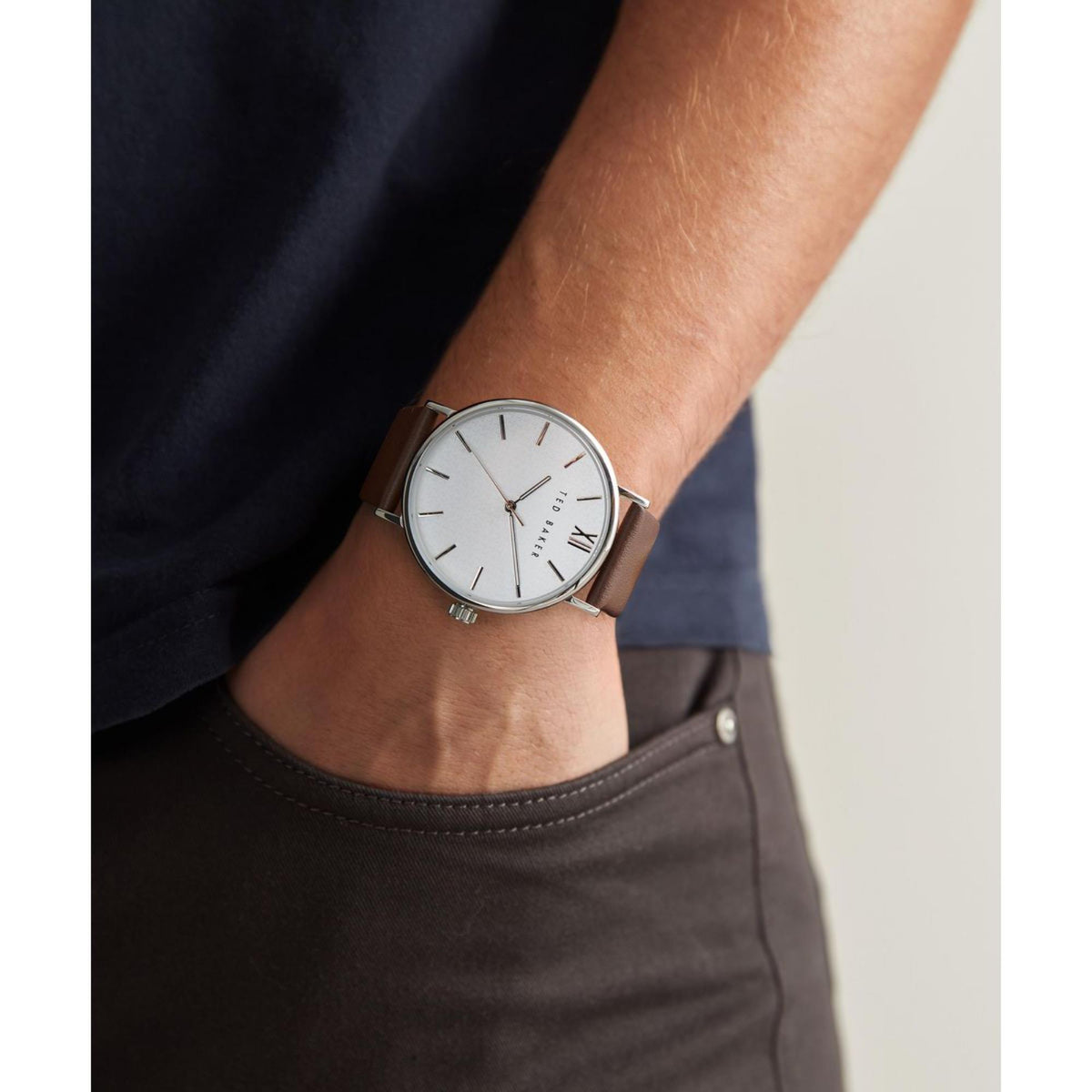 Wristwatch on wrist with white dial, brown leather strap and silver-tone case