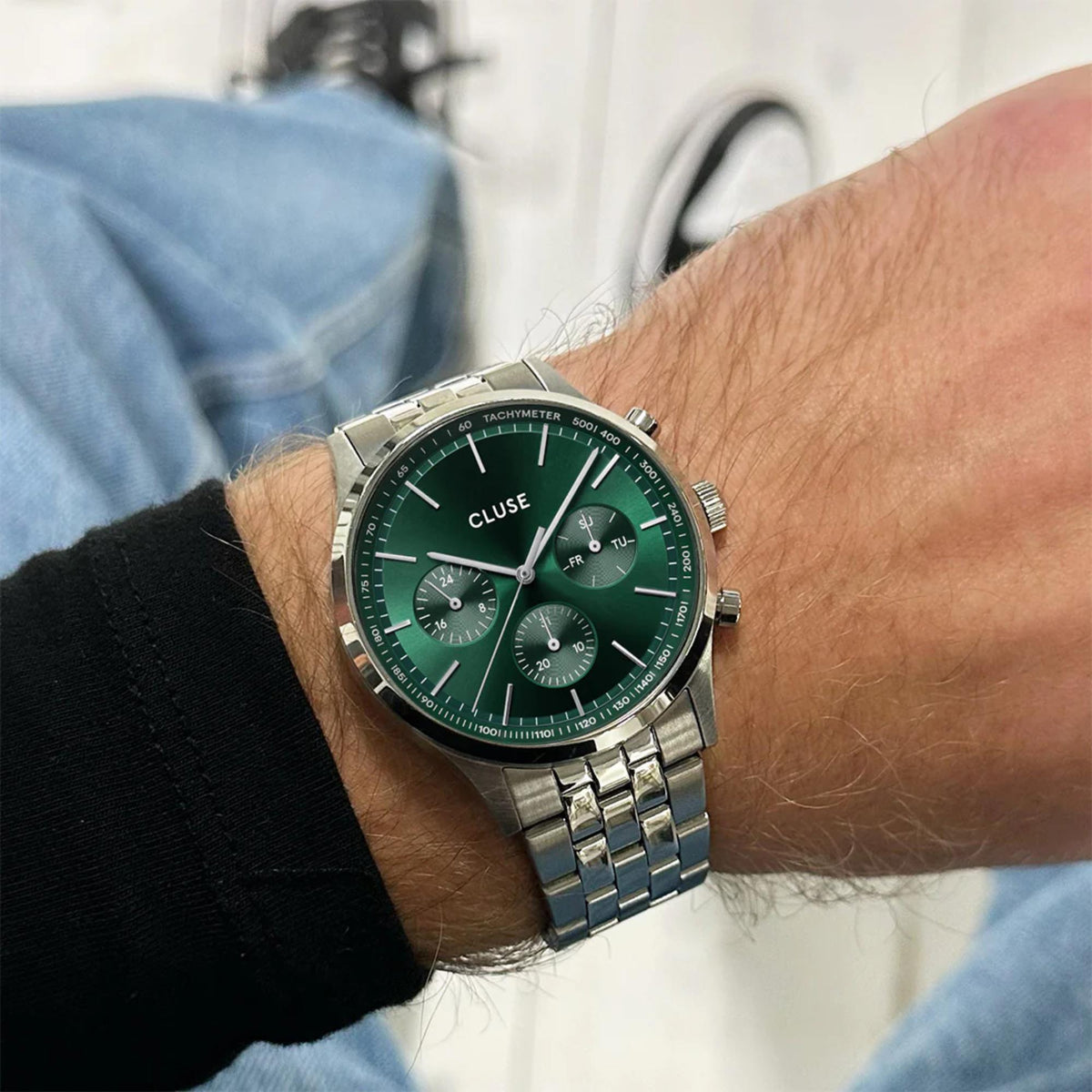 Men's quartz chronograph watch on wrist, green dial with steel bracelet