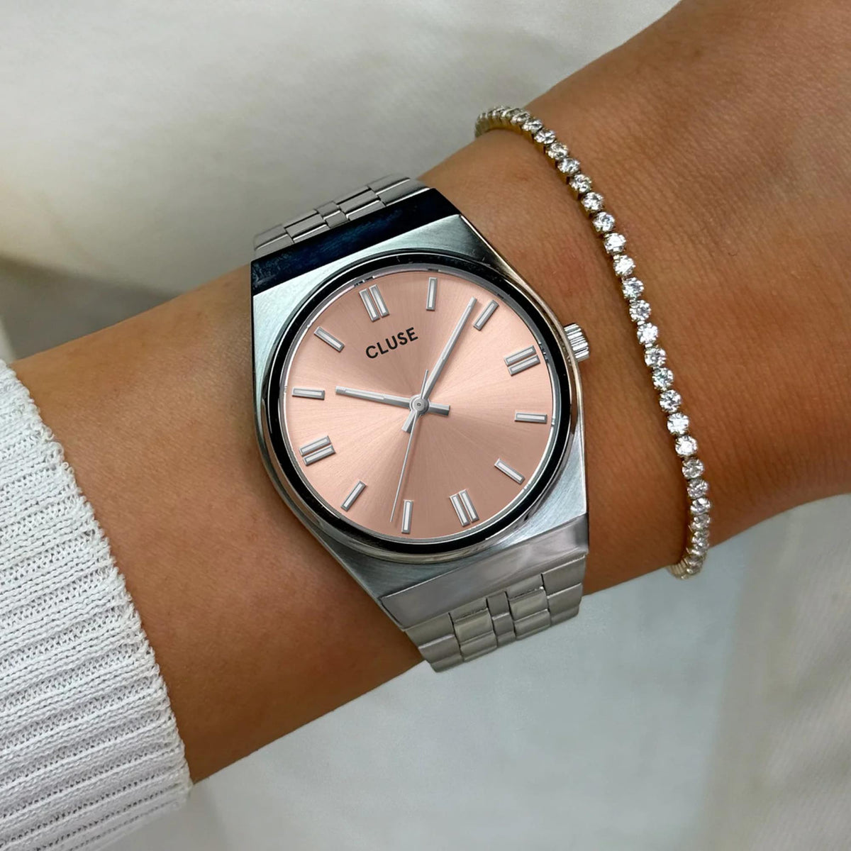 Women's steel wristwatch with pink dial and link bracelet, worn on wrist