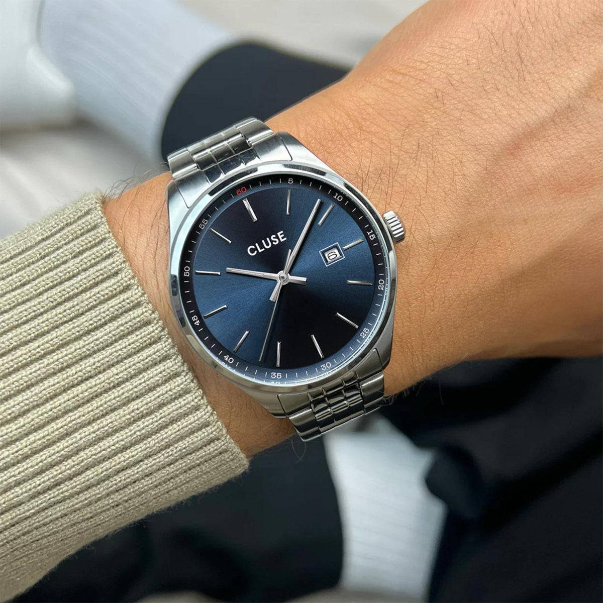 Men's steel wristwatch on wrist, blue dial with baton markers and date window