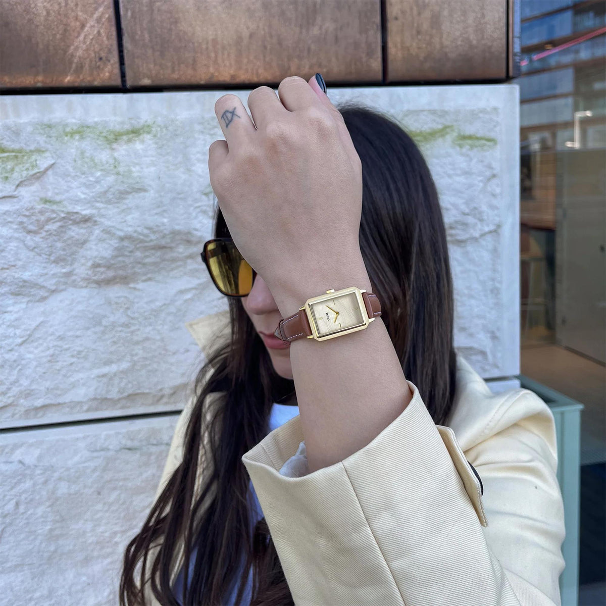 Women's quartz watch on wrist with gold case and brown leather strap