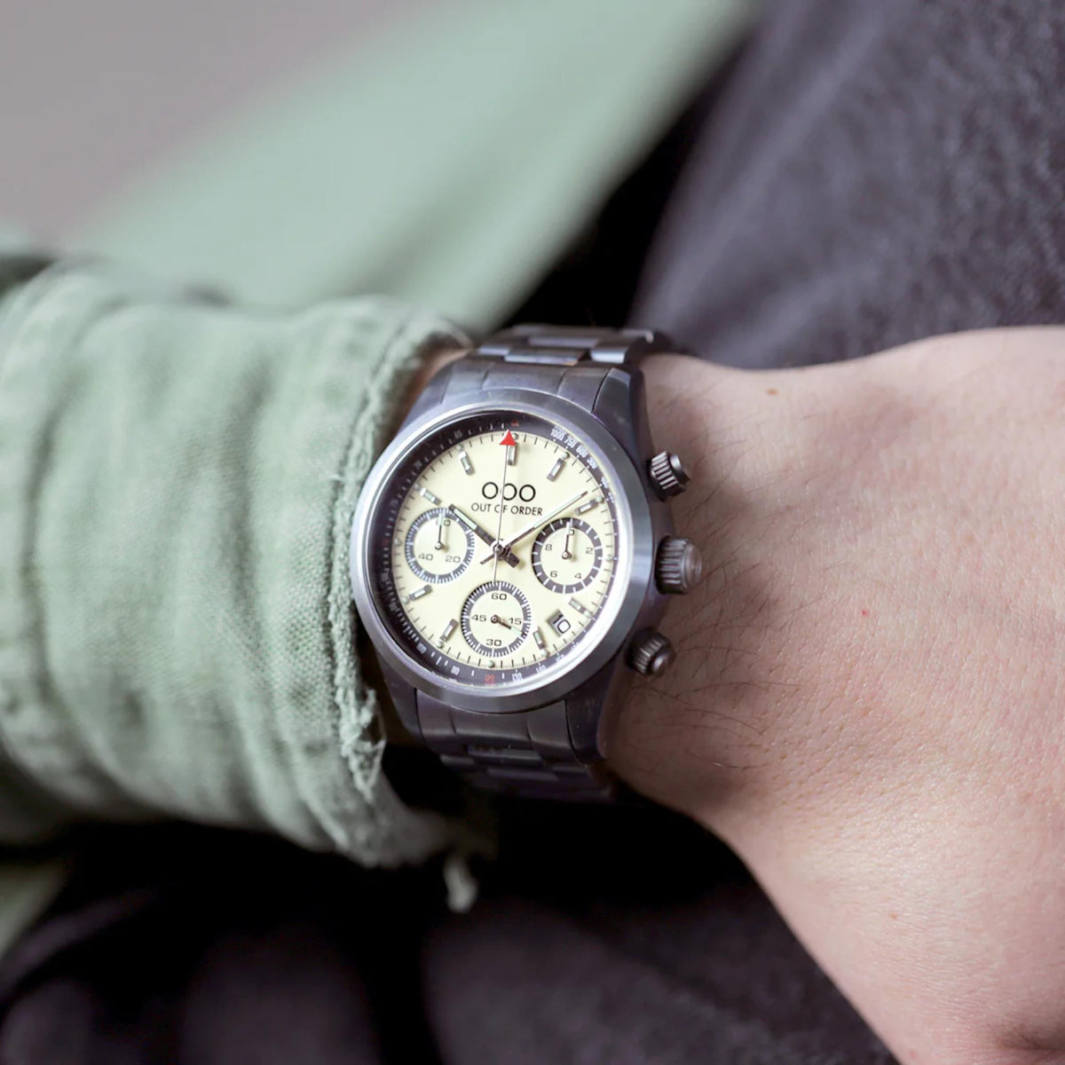 Men's sporty quartz chronograph watch on wrist with cream dial and steel strap