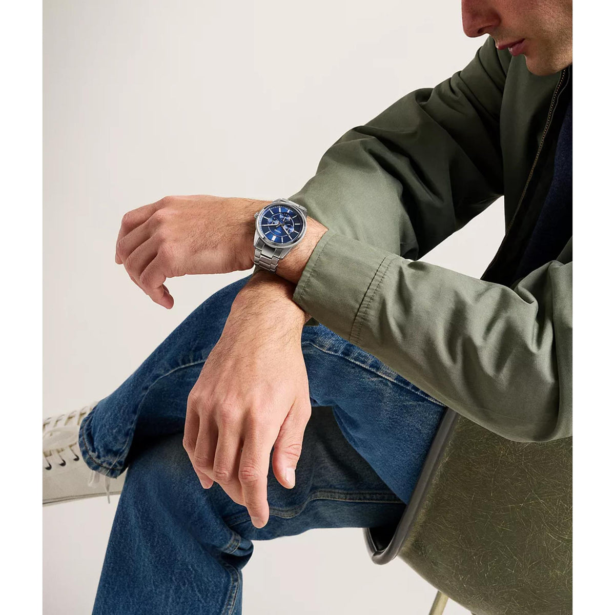 Chronograph watch on wrist with blue dial and stainless steel bracelet links