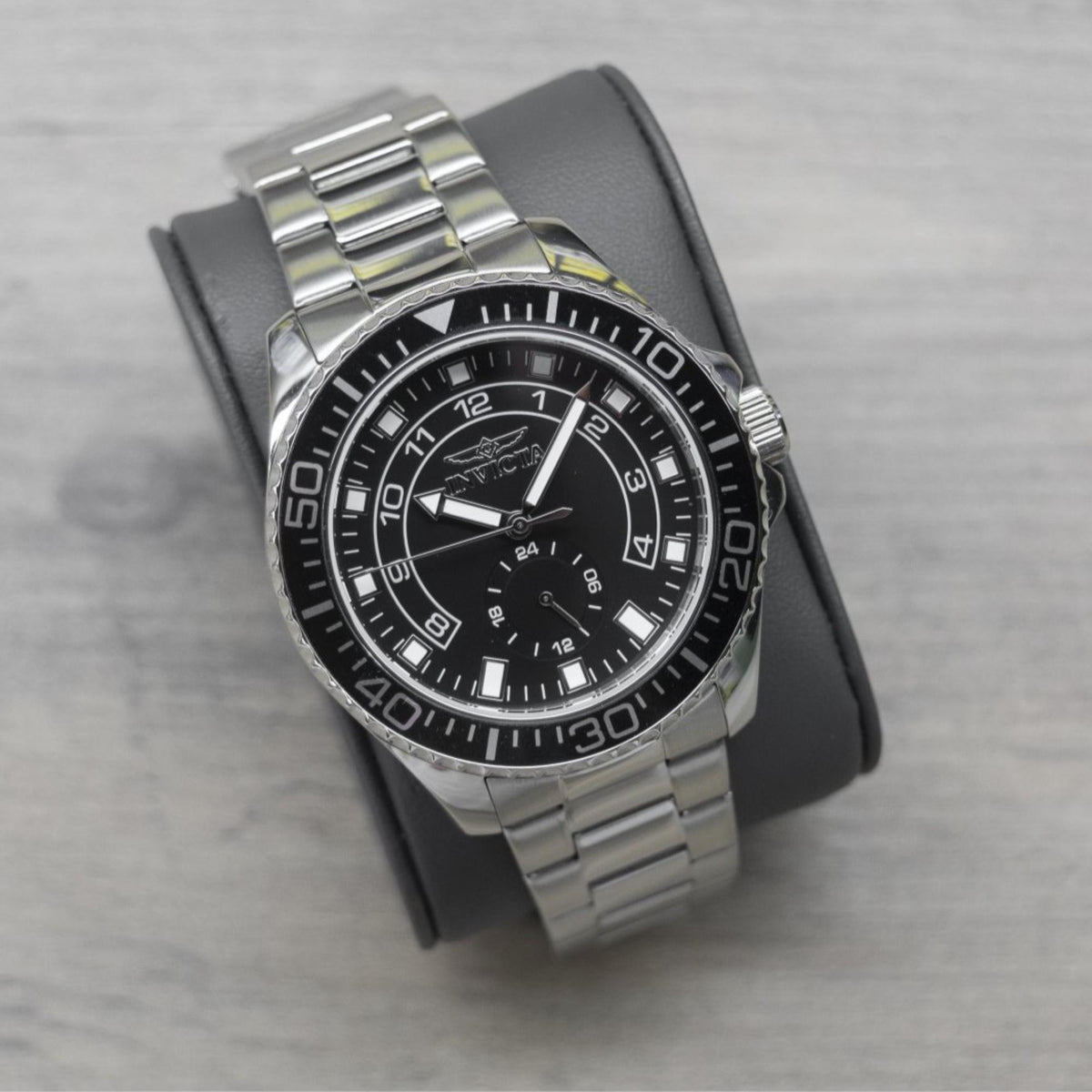 Invicta Pro Diver men's watch with black dial and steel bracelet, angled view with cushion backing