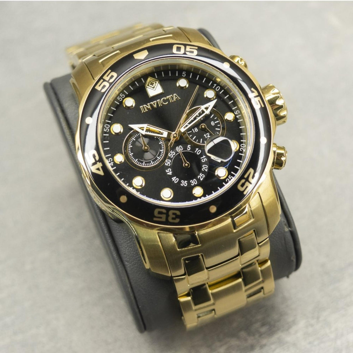Gold-tone diver watch with black dial and gold bezel, worn on black strap