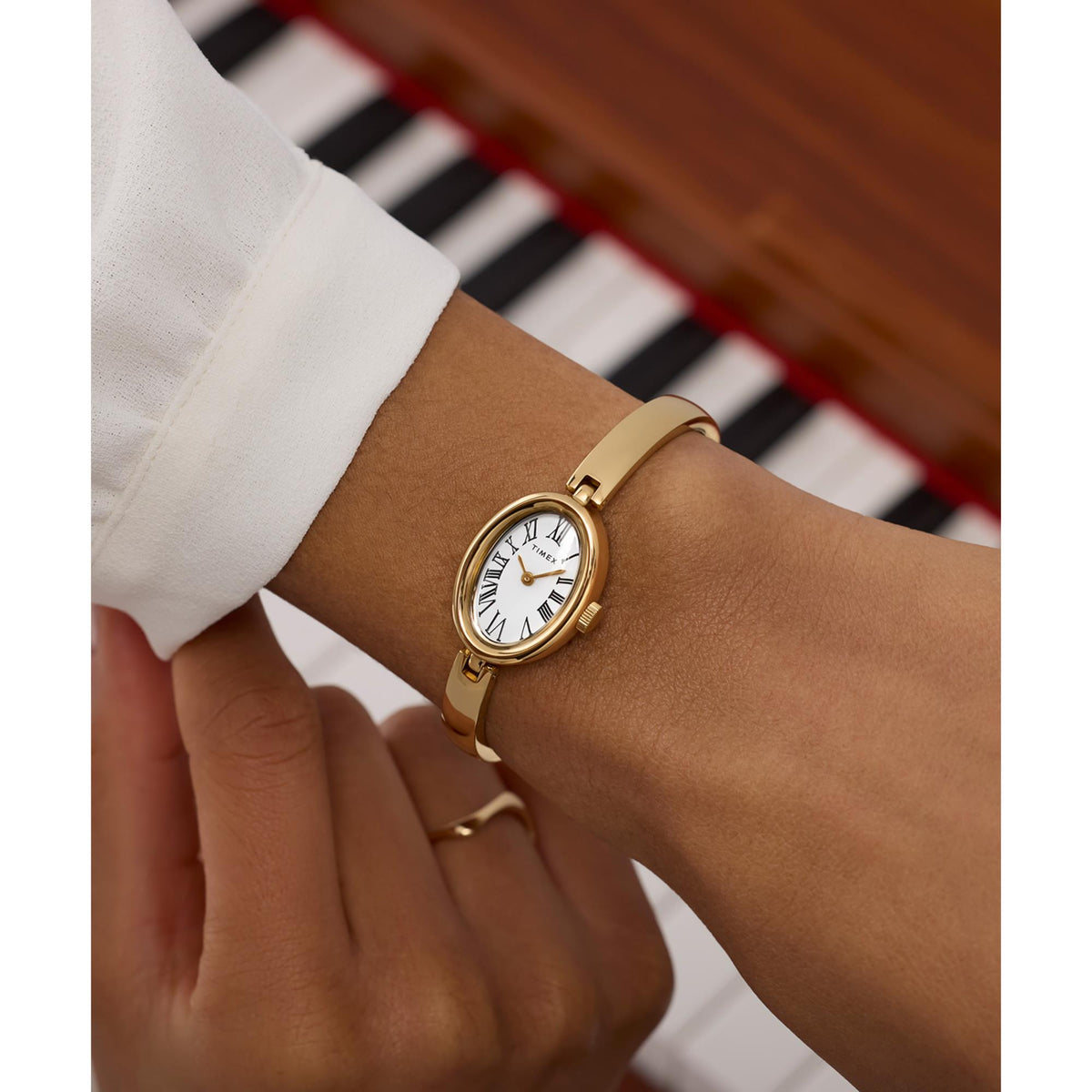 Gold-tone ladies quartz wrist watch on wrist with white dial and Roman numerals
