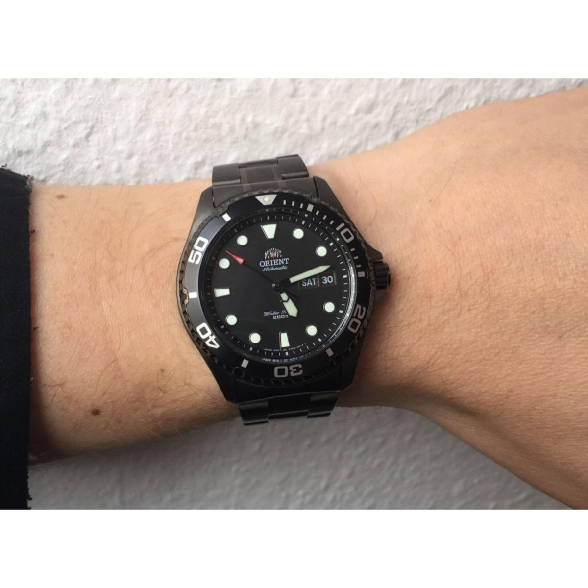 Men's automatic diver watch on wrist, black dial with illuminated hour markers