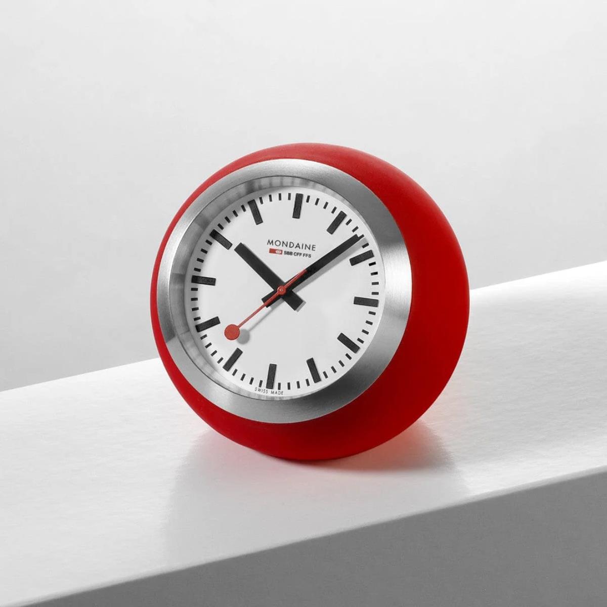 Mondaine 6cm Globe table clock A660.30335.16SBP styled on a shelf featuring red casing and a white Swiss Railways dial