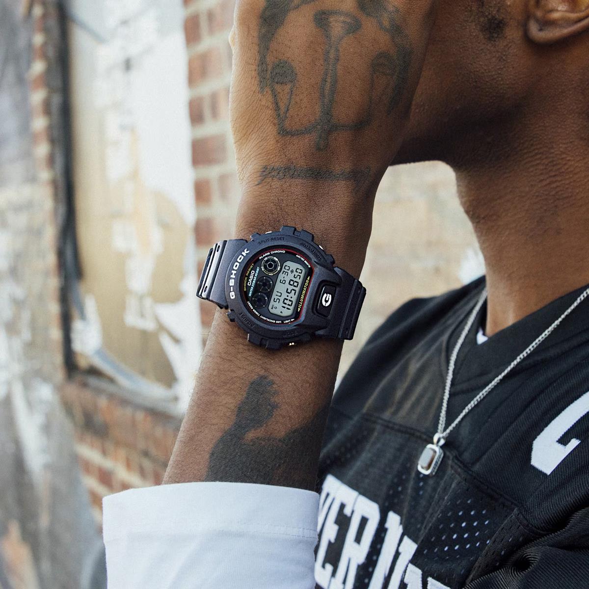 Casio G-Shock 6900 Series DW-6900RL-1ER digital watch showcased on a wrist against an urban brick backdrop