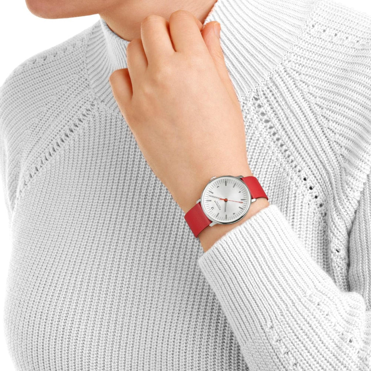 Close-up of a woman wearing the Mondaine Doppio MLE.33110.LCV watch on her left wrist, paired with a cozy, textured white knit sweater