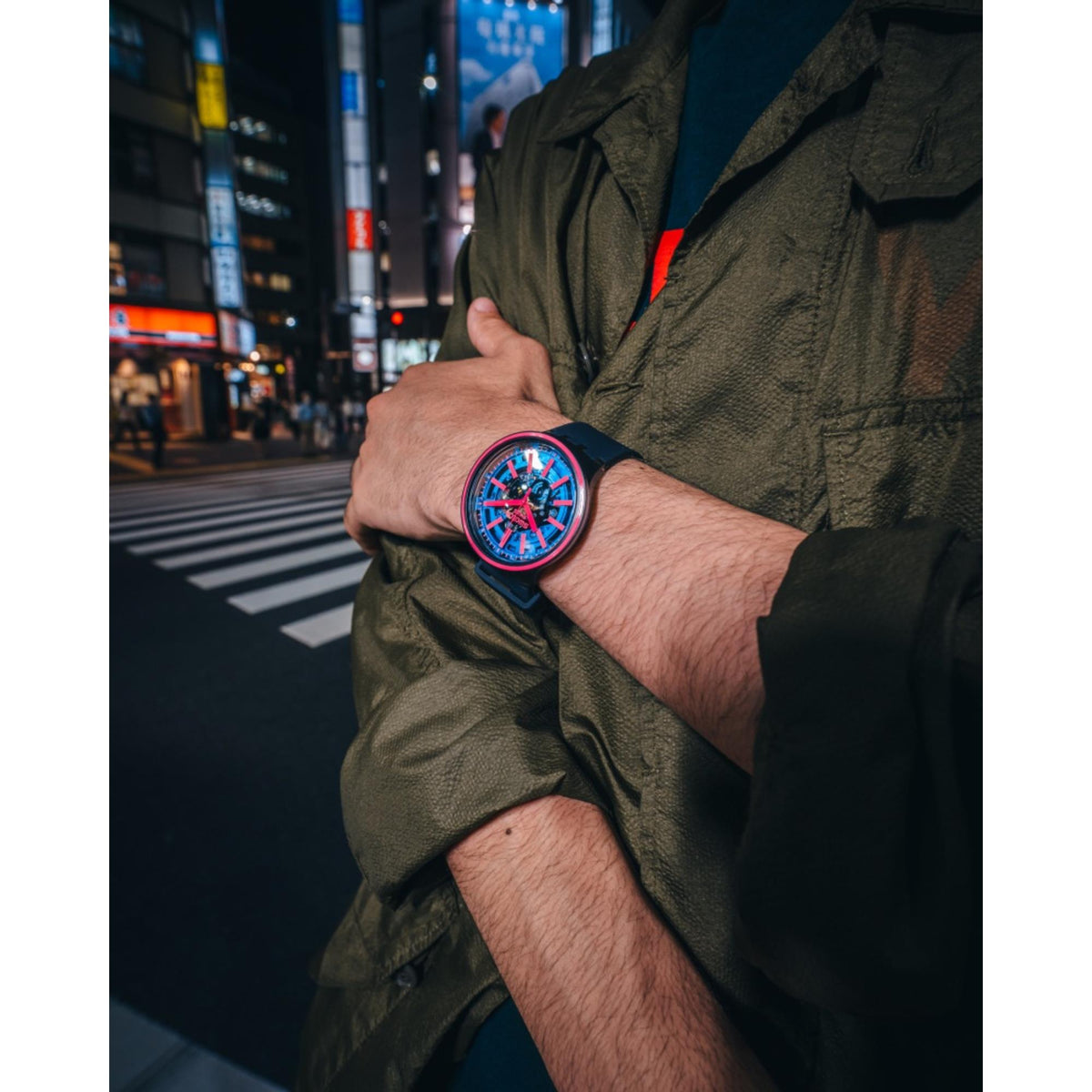 Swatch blue dial silicone strap watch with pink accents, worn on wrist