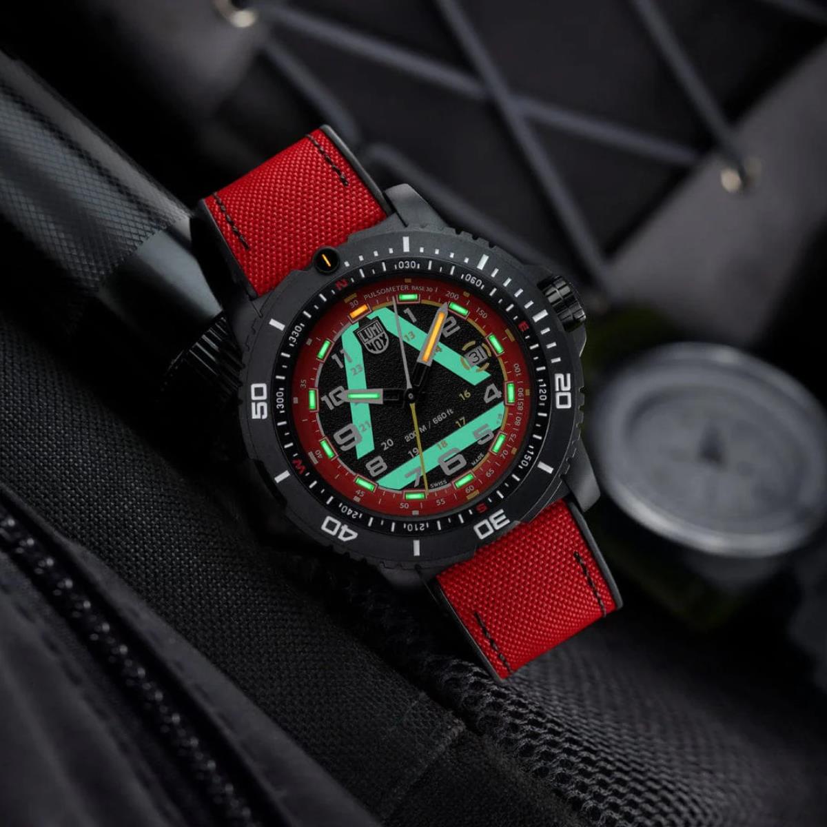 Luminox ICE-SAR watch glowing in the dark, highlighting its luminous green and orange dial markings against a red and black strap