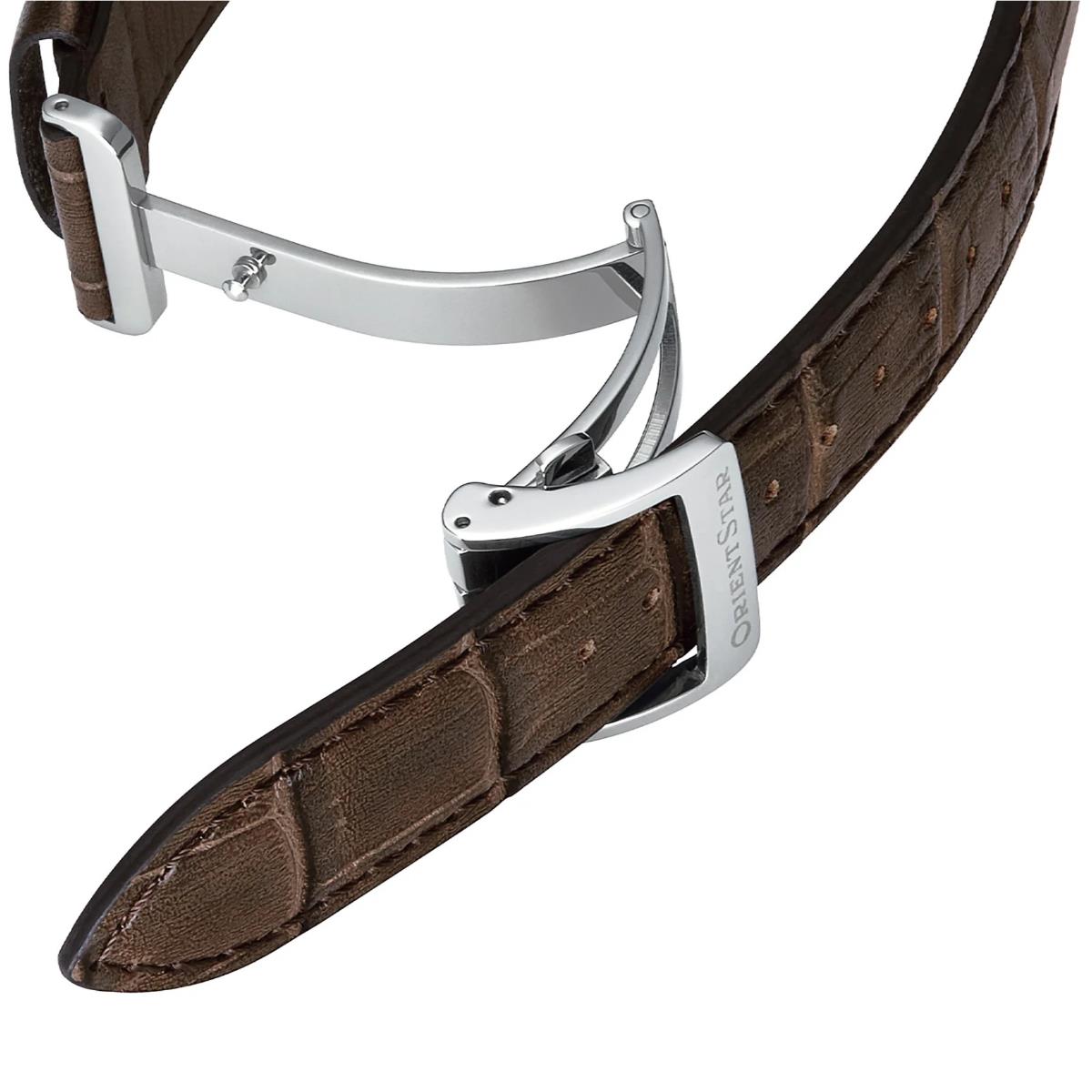 Silver watch case with brown leather strap and buckle, side view