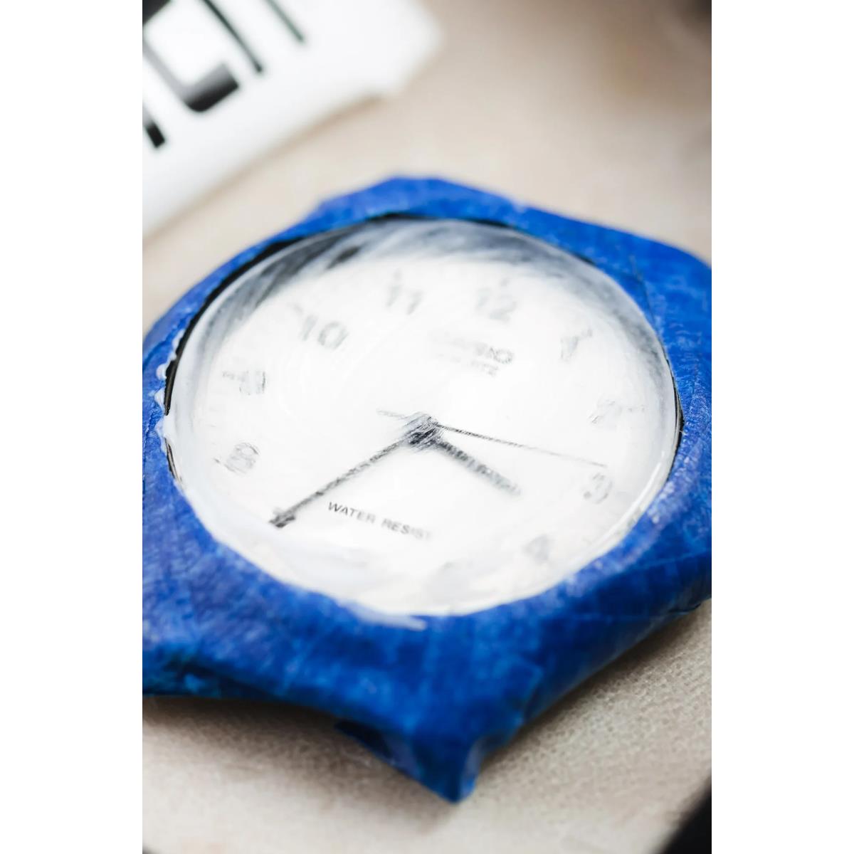 Wristwatch face on blue polishing pad for plastic crystal cleaning