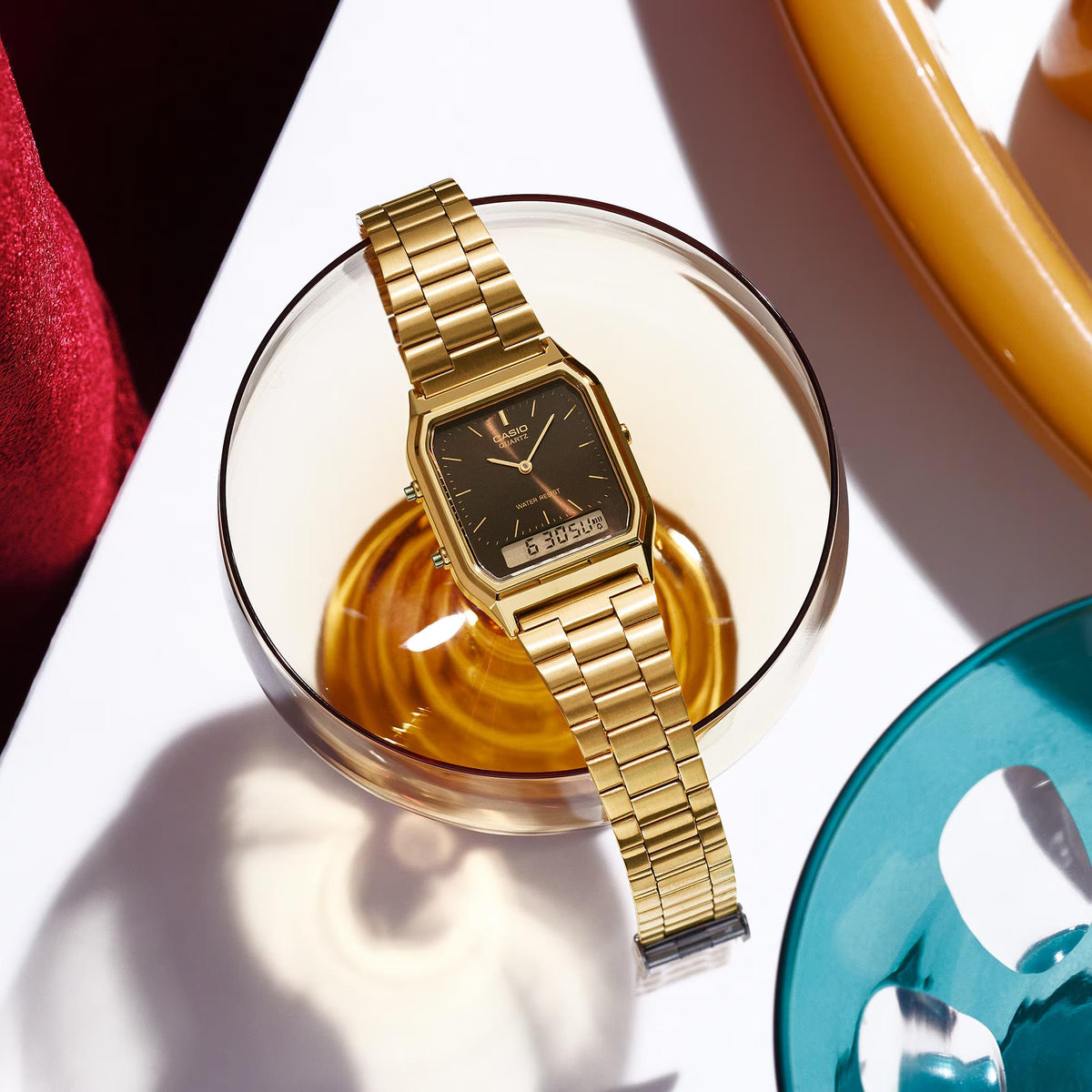 Gold-tone metal bracelet women’s watch with dark rectangular dial and digital display window.