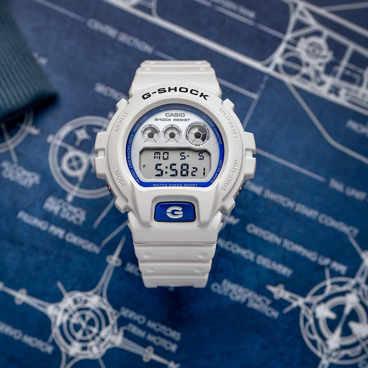 Casio G-Shock DW-6900HDS-7ER white digital watch top-down view on blueprint background