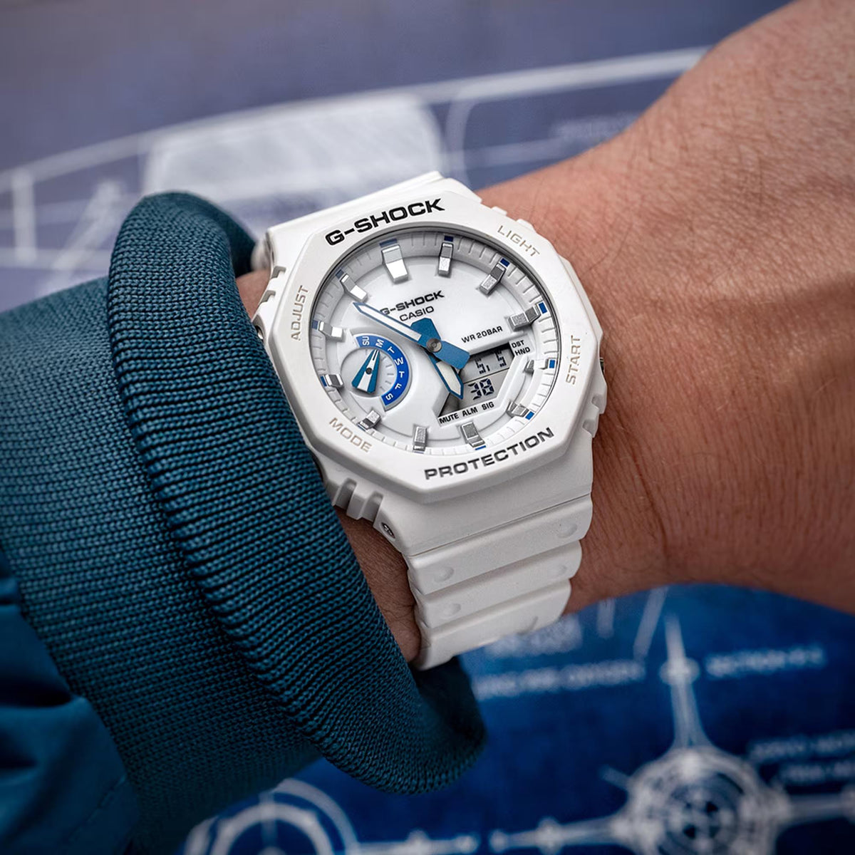 White resin G-Shock watch on wrist, blue subdials, analog hands, digital readout