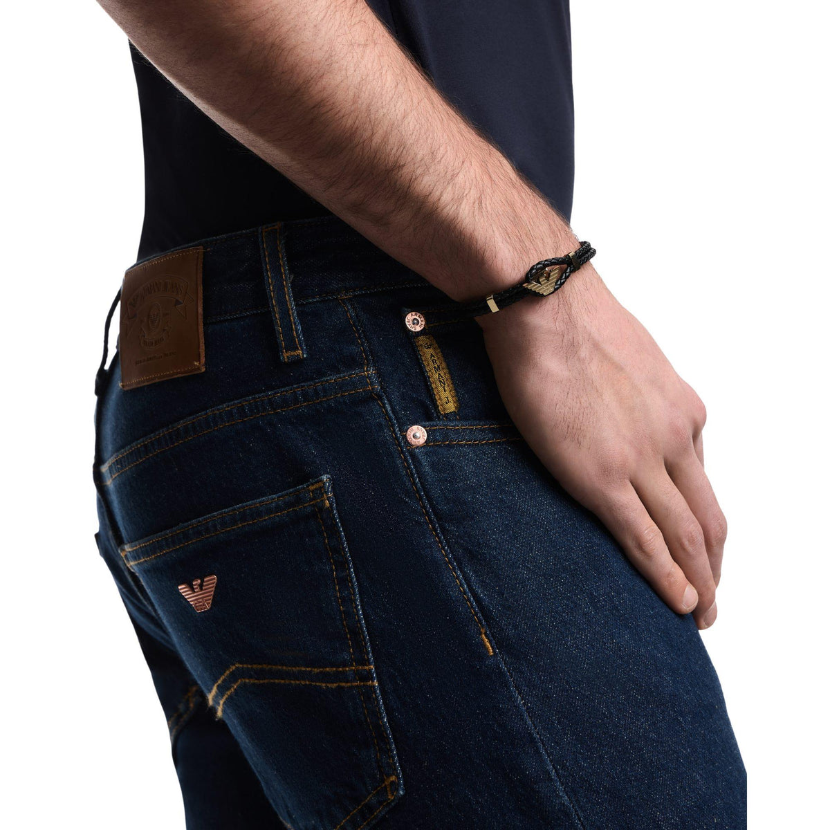 Men's black braided leather ID bracelet on wrist, gold-tone emblem and clasp