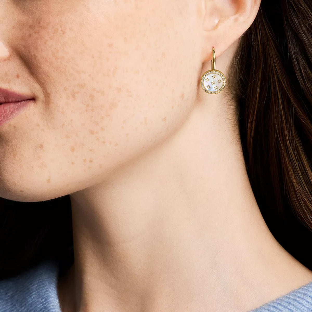 Worn gold-tone drop earring with oval mother-of-pearl and crystal star details