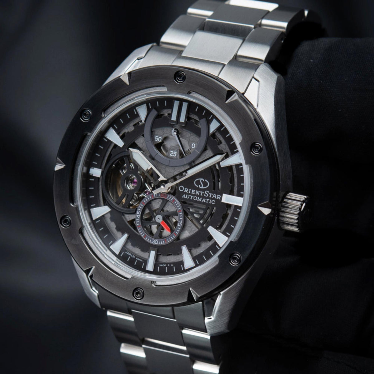 Men's automatic skeleton watch close-up, black dial with exposed gears and bezel.