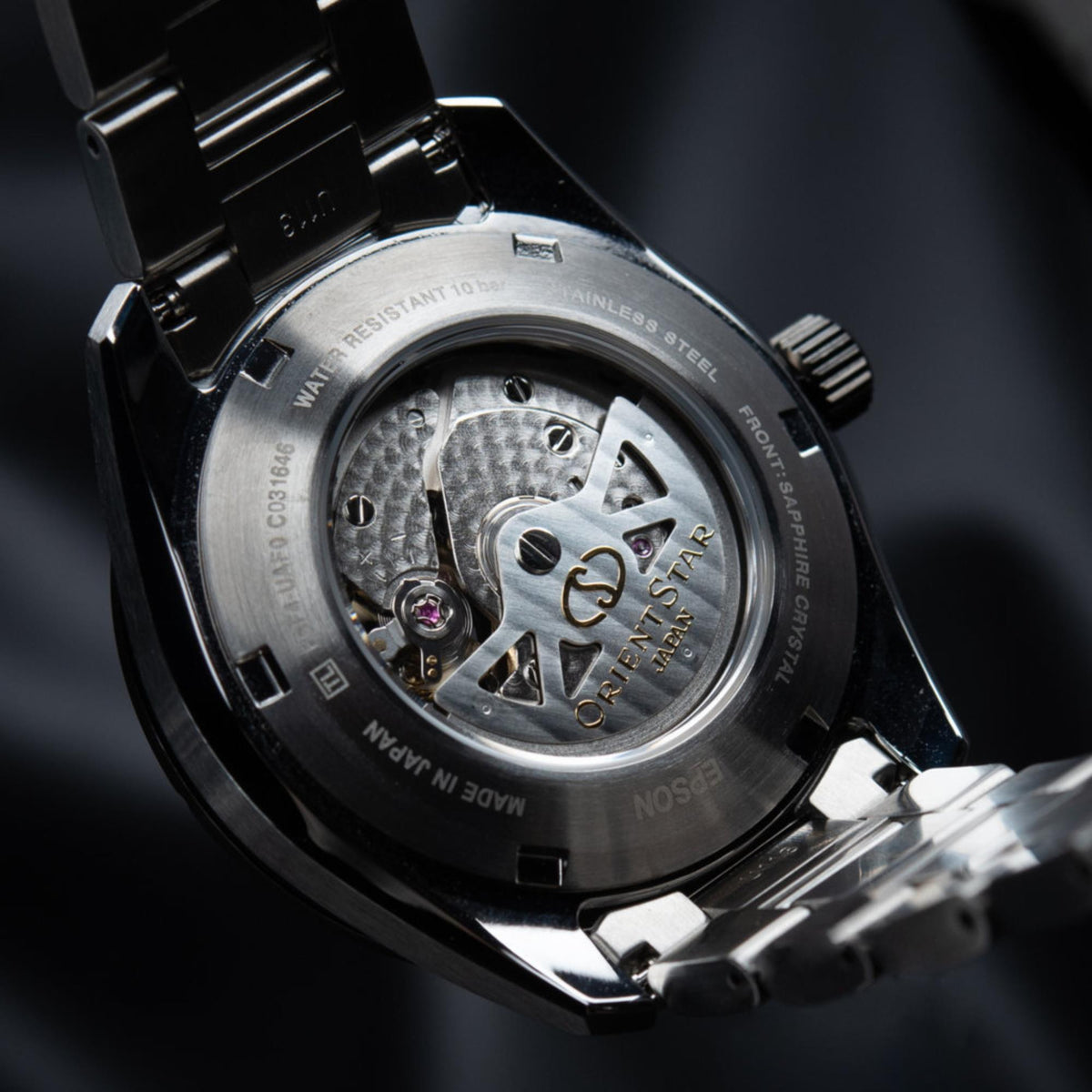 Orient Star automatic skeleton watch open caseback with visible gears and steel bracelet