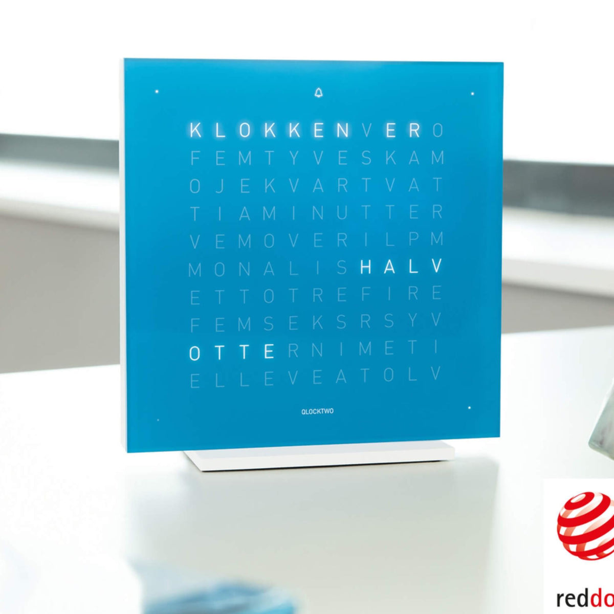 Blue QLOCKTWO table clock on white stand with word grid letters, angled