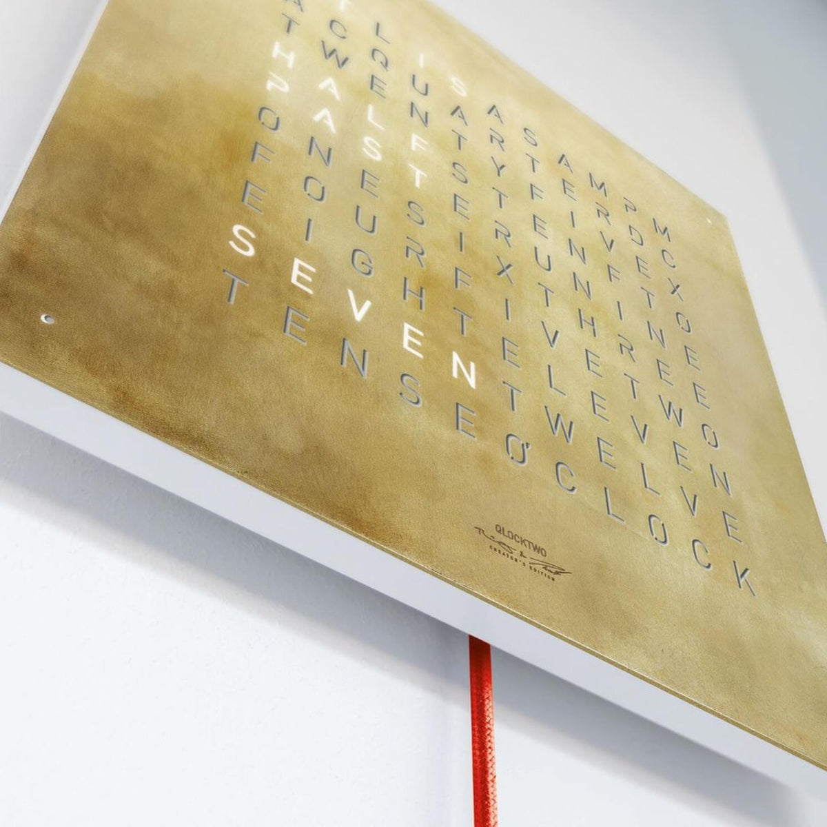 Close-up of gold QLOCKTWO wall clock dial with English letter grid