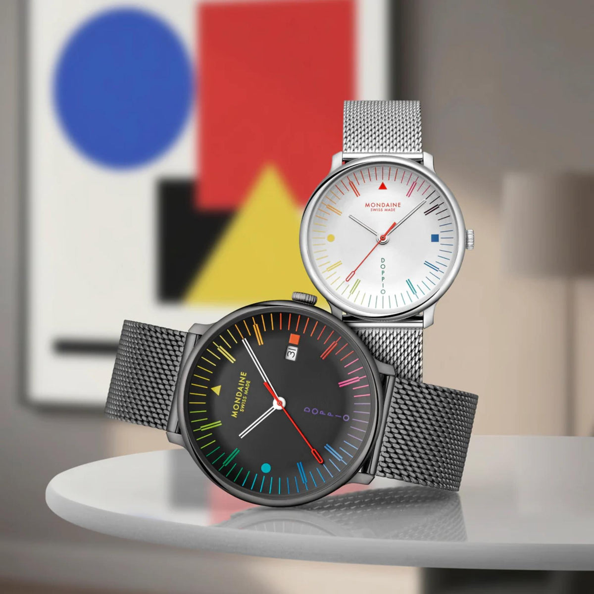 Mondaine Doppio MLE.33112.SM watch with a white dial is presented next to its counterpart version featuring a black dial and dark mesh strap