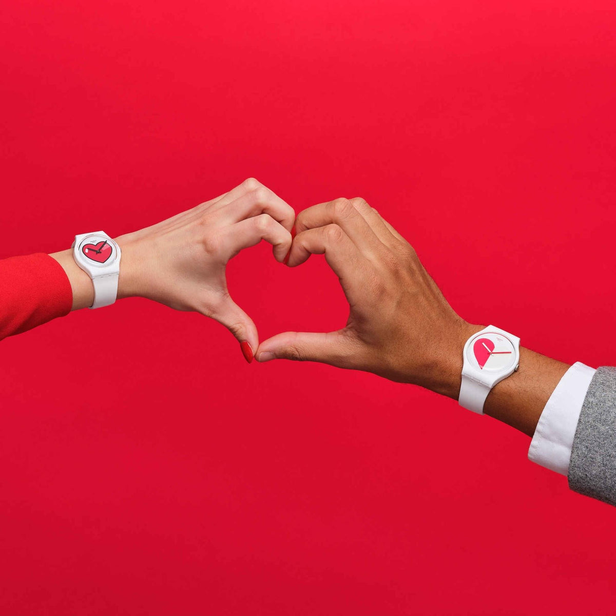 Two hands forming a heart against a red background, one wearing the white Swatch Originals Love O'Clock watch (GW718) and the other wearing a matching red Swatch watch