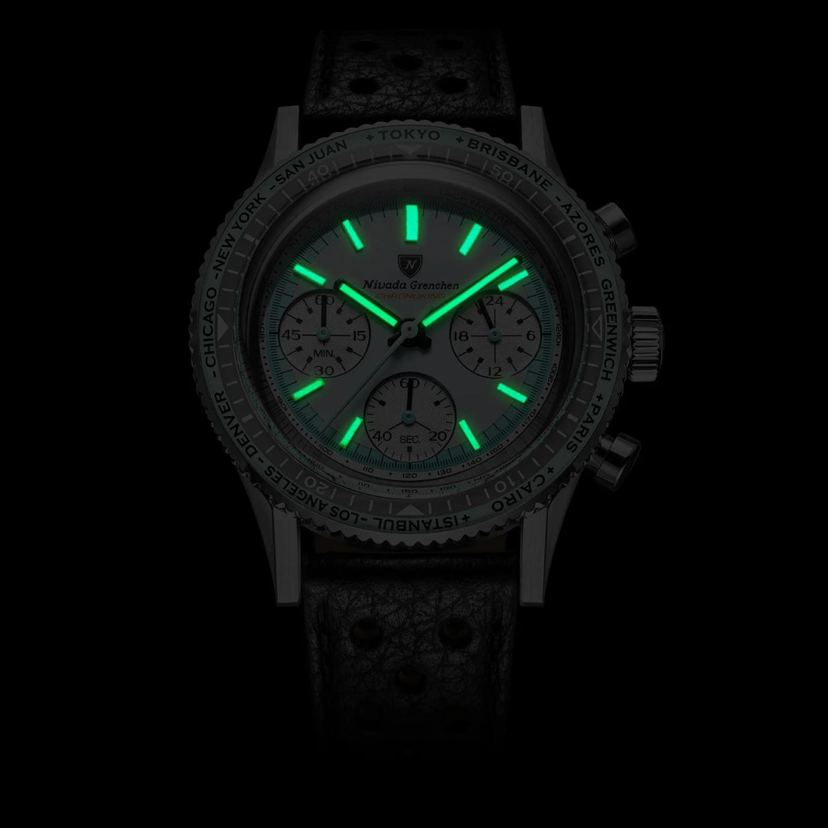 Close-up view of the Nivada Grenchen Chronoking watch in the dark, showcasing its bright green luminous hour markers and hands